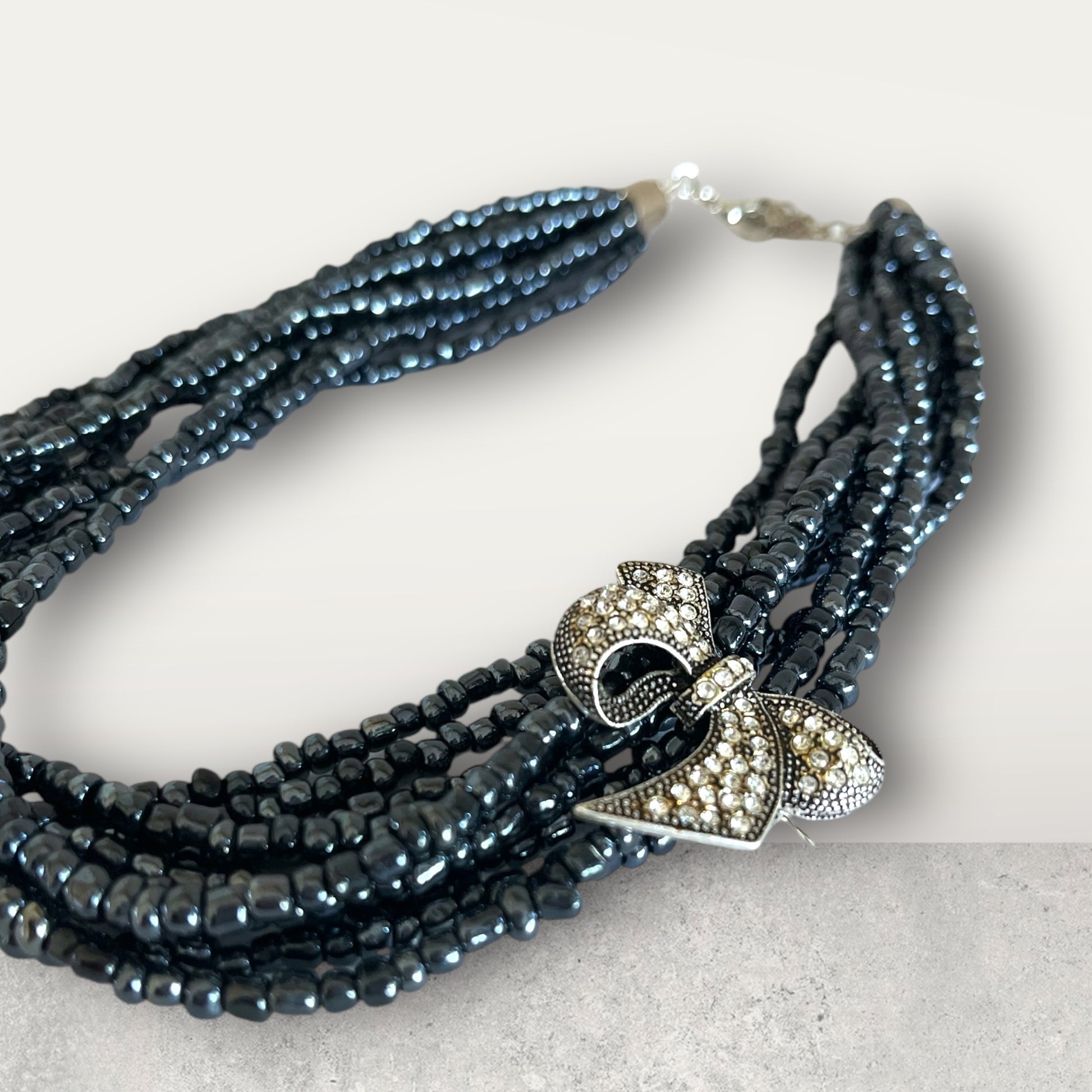 Semra Ascioglu multi-strand midnight-blue beaded necklace with a crystal-encrusted vintage bow charm.